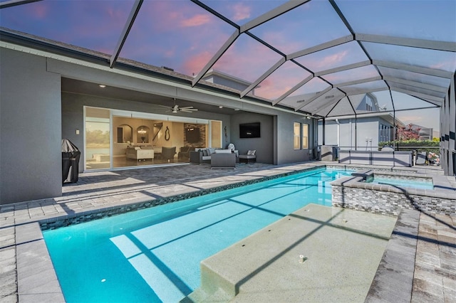 pool at dusk with outdoor lounge area, ceiling fan, a lanai, an in ground hot tub, and a patio