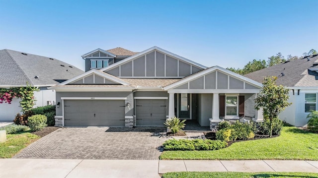 view of front of house with a porch, a garage, and a front lawn