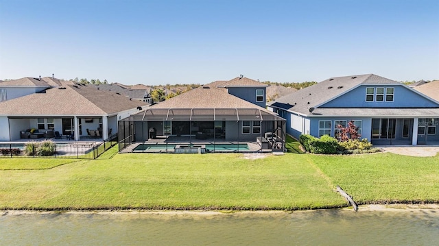 rear view of property with glass enclosure, a yard, and a water view