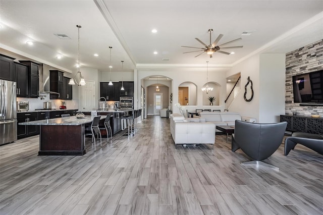 living room featuring light hardwood / wood-style floors, ceiling fan with notable chandelier, and ornamental molding