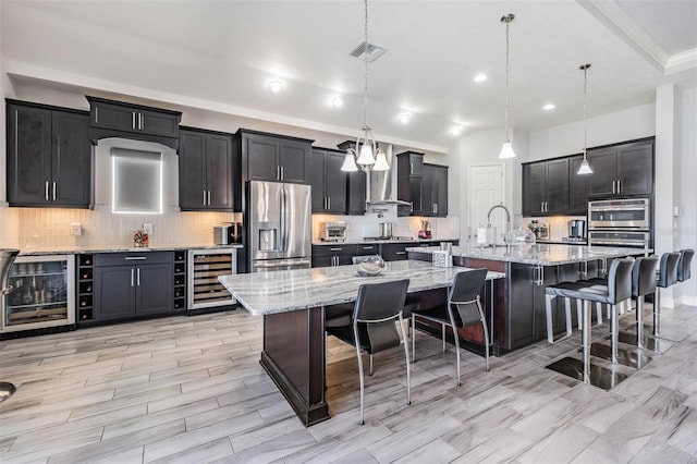 kitchen featuring decorative light fixtures, a spacious island, stainless steel appliances, and beverage cooler