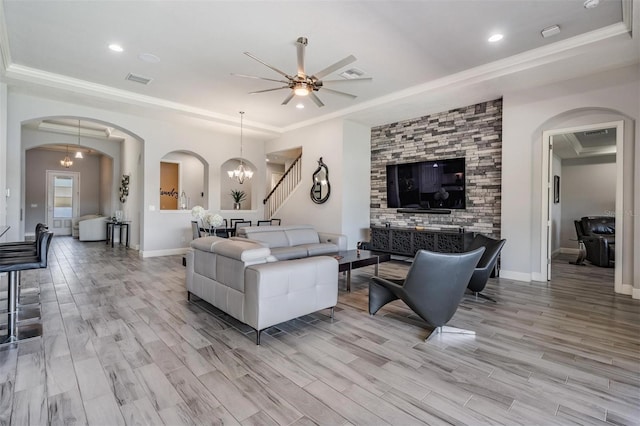 living room featuring ornamental molding, ceiling fan with notable chandelier, and light wood-type flooring