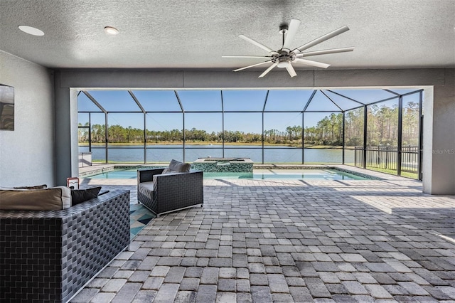 view of pool with glass enclosure, ceiling fan, a patio area, an in ground hot tub, and a water view