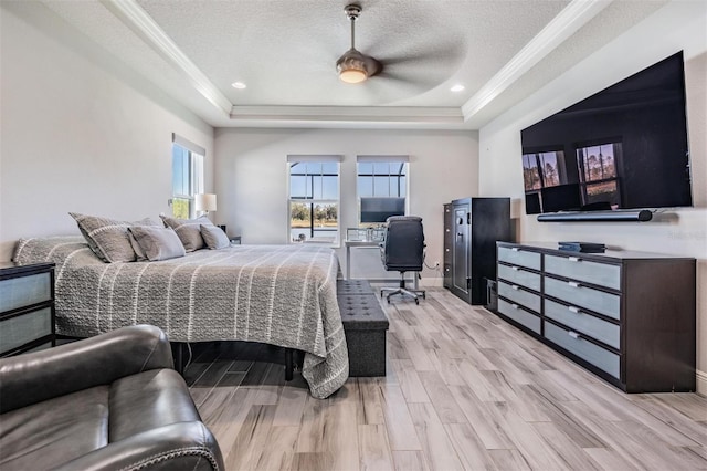 bedroom featuring ceiling fan, light wood-type flooring, a textured ceiling, and a tray ceiling