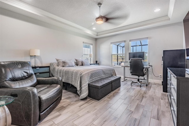 bedroom with a tray ceiling, ceiling fan, light hardwood / wood-style flooring, and a textured ceiling