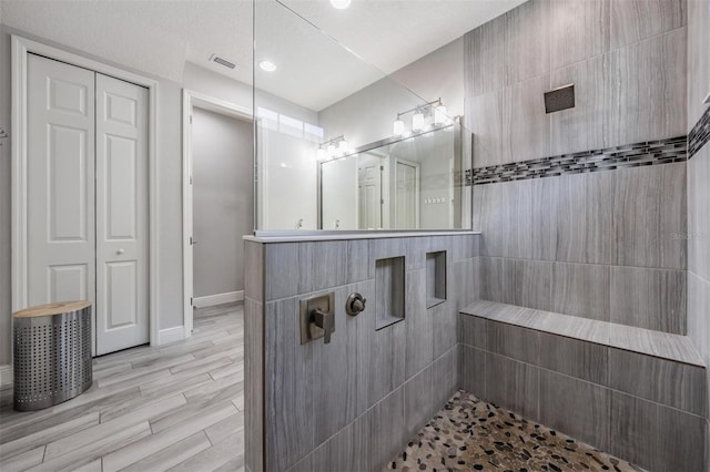 bathroom featuring a tile shower, hardwood / wood-style floors, vanity, and a textured ceiling