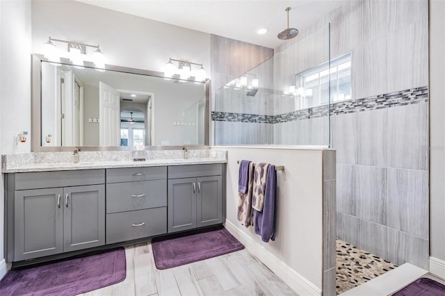 bathroom with hardwood / wood-style flooring, vanity, and a tile shower