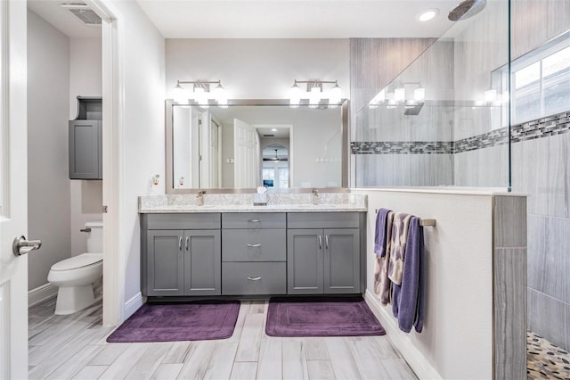 bathroom featuring toilet, hardwood / wood-style floors, vanity, and tiled shower