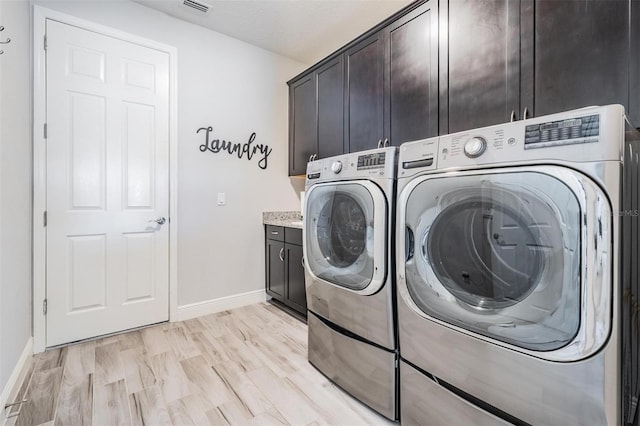 washroom with washing machine and clothes dryer, light hardwood / wood-style flooring, cabinets, and a textured ceiling