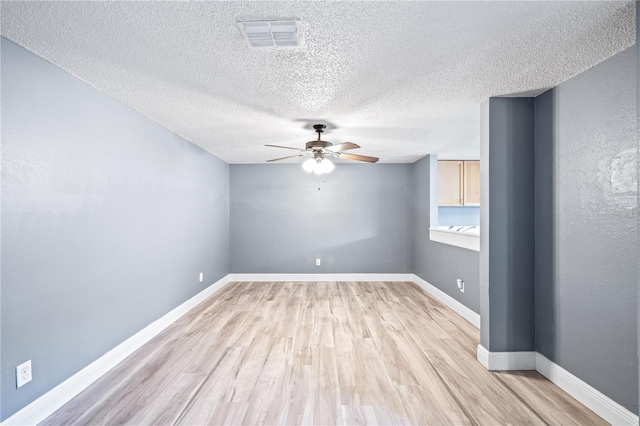 empty room with a ceiling fan, visible vents, light wood-style flooring, and baseboards