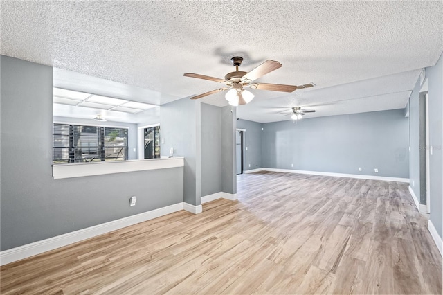 empty room featuring a ceiling fan, a textured ceiling, baseboards, and wood finished floors