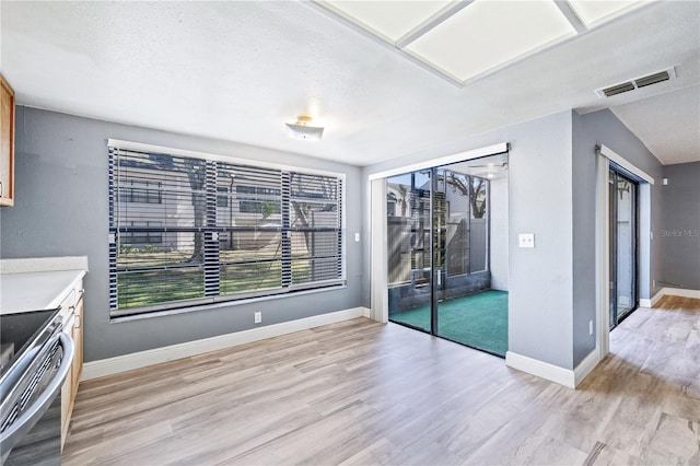 unfurnished dining area with light wood-type flooring and a textured ceiling