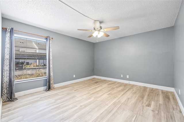 unfurnished room with ceiling fan, a textured ceiling, baseboards, and wood finished floors