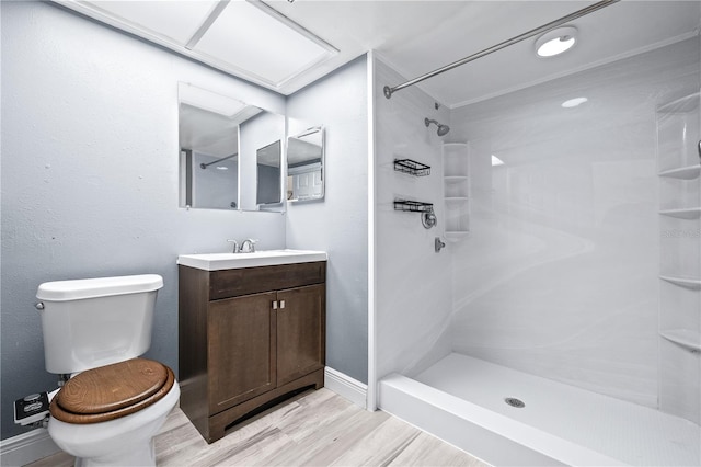 full bath featuring toilet, vanity, wood finished floors, baseboards, and walk in shower