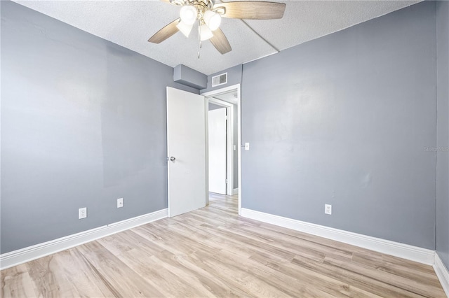 empty room featuring a textured ceiling, light wood-type flooring, and ceiling fan