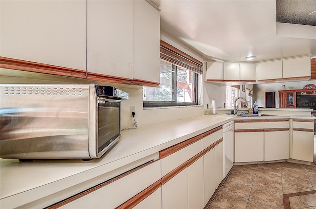 kitchen featuring dishwasher, white cabinetry, and sink