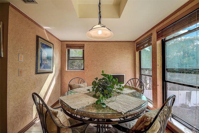 tiled dining space featuring plenty of natural light and crown molding