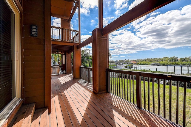 wooden terrace featuring a lawn and a water view