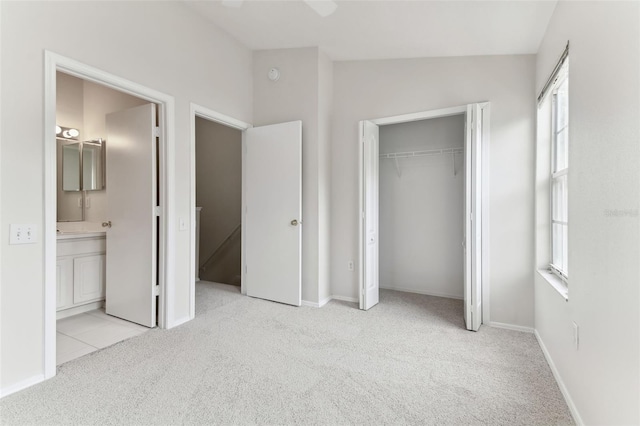 unfurnished bedroom featuring vaulted ceiling, connected bathroom, multiple windows, light carpet, and a closet