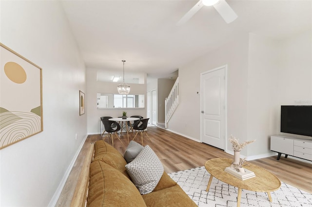 living room featuring wood-type flooring and ceiling fan with notable chandelier