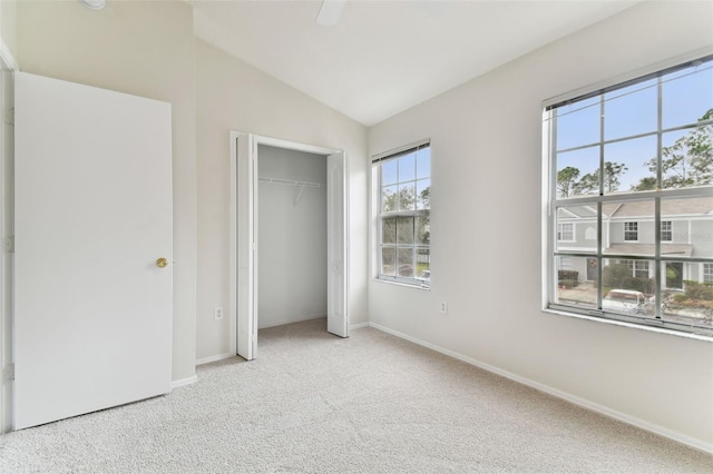 unfurnished bedroom featuring light colored carpet, vaulted ceiling, and a closet