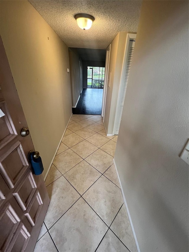 hall with light tile patterned floors and a textured ceiling