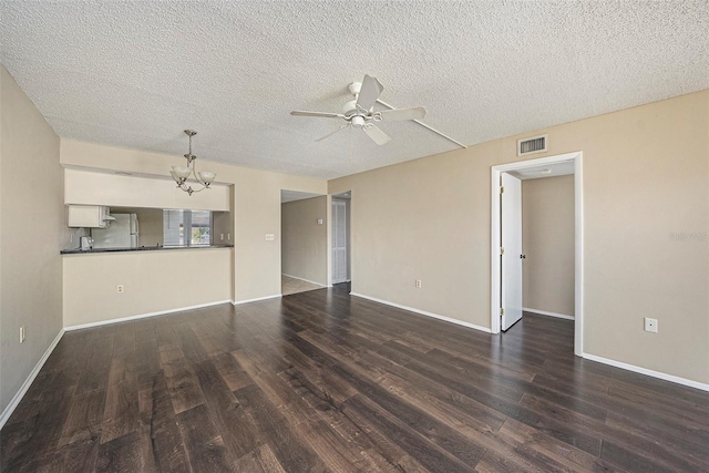 unfurnished living room with dark wood-type flooring, ceiling fan with notable chandelier, and a textured ceiling