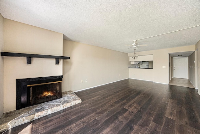 unfurnished living room featuring ceiling fan, a textured ceiling, a fireplace, and wood-type flooring