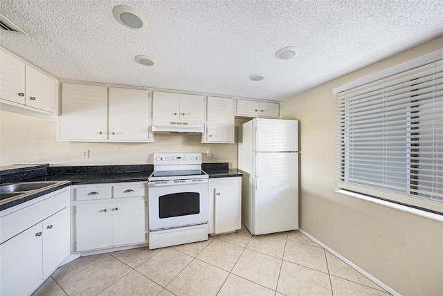 kitchen with white appliances, a textured ceiling, white cabinets, and light tile patterned flooring