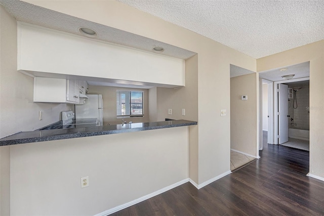 kitchen featuring dark hardwood / wood-style floors, white cabinetry, white refrigerator, range, and a textured ceiling