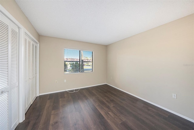 unfurnished bedroom featuring a textured ceiling and dark hardwood / wood-style flooring