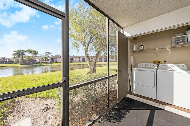 clothes washing area with a water view, separate washer and dryer, and a wealth of natural light