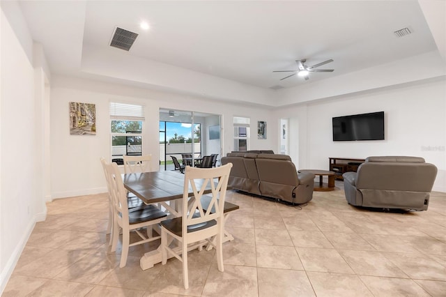 tiled dining room featuring ceiling fan and a tray ceiling