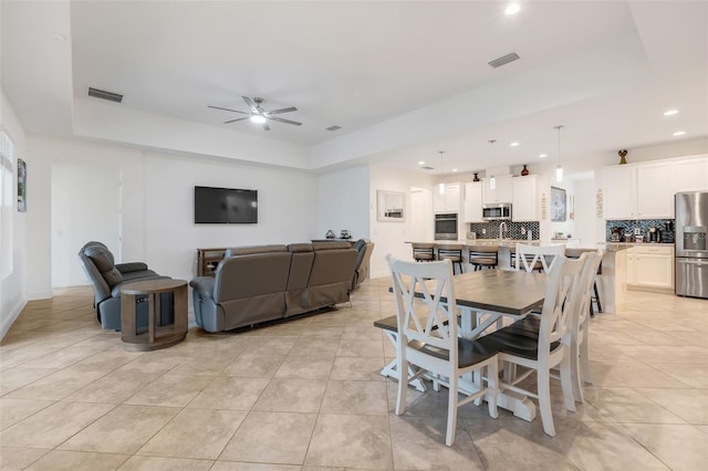 dining space featuring a raised ceiling, ceiling fan, and light tile patterned floors