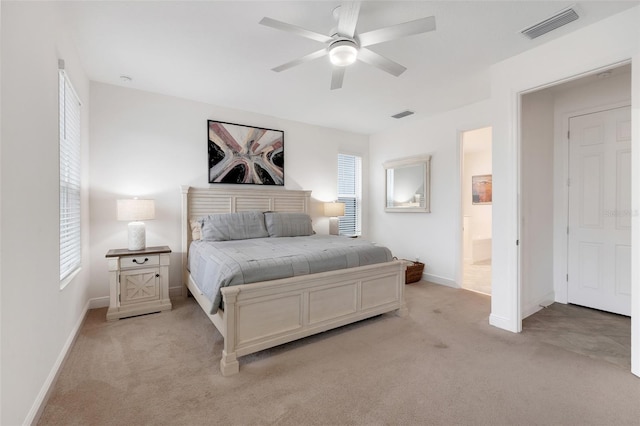 carpeted bedroom with ensuite bath and ceiling fan