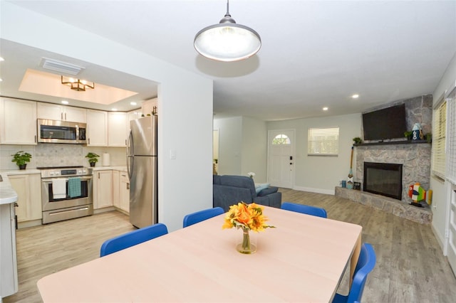 dining space with a stone fireplace and light wood-type flooring