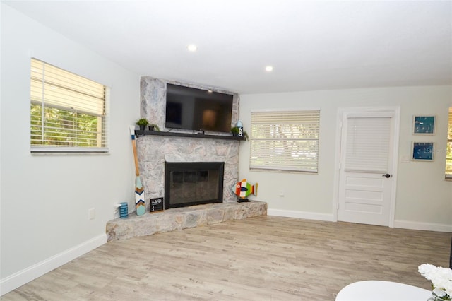 living room with light hardwood / wood-style floors, a fireplace, and a wealth of natural light