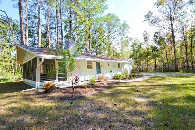 rear view of property with a lawn and a sunroom