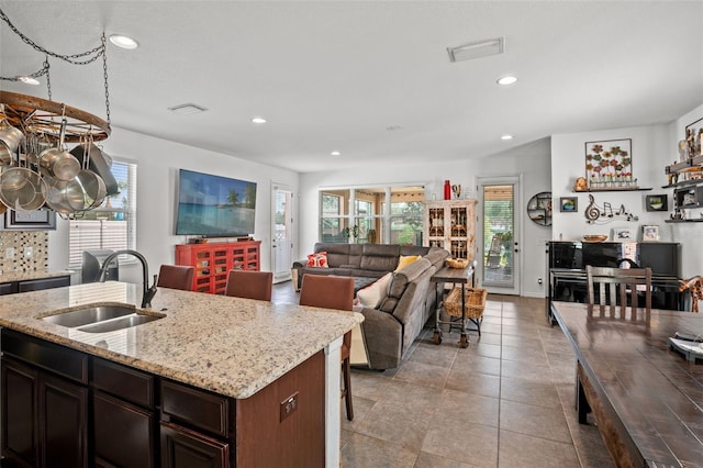 kitchen featuring plenty of natural light, dark brown cabinetry, sink, and a kitchen island with sink