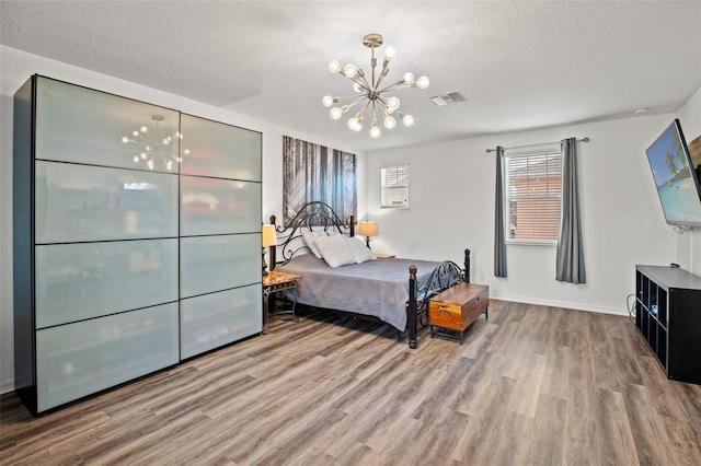 bedroom with wood-type flooring, a textured ceiling, and a notable chandelier