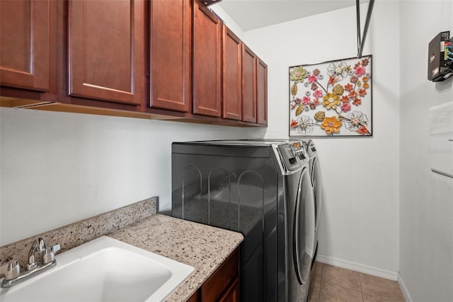 laundry room featuring cabinets, light tile patterned floors, sink, and washing machine and clothes dryer