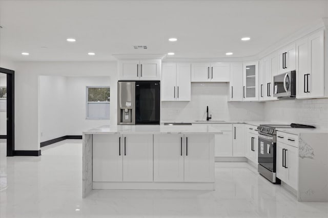 kitchen with white cabinets, stainless steel appliances, light stone counters, and sink