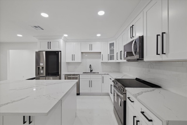 kitchen featuring stainless steel appliances, white cabinetry, sink, and light stone countertops