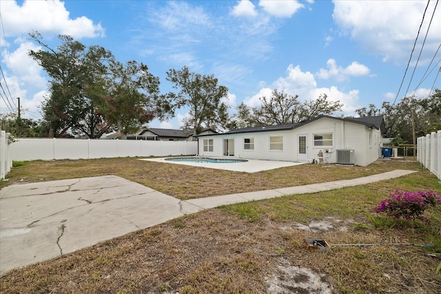 rear view of property with a lawn, cooling unit, a fenced in pool, and a patio area