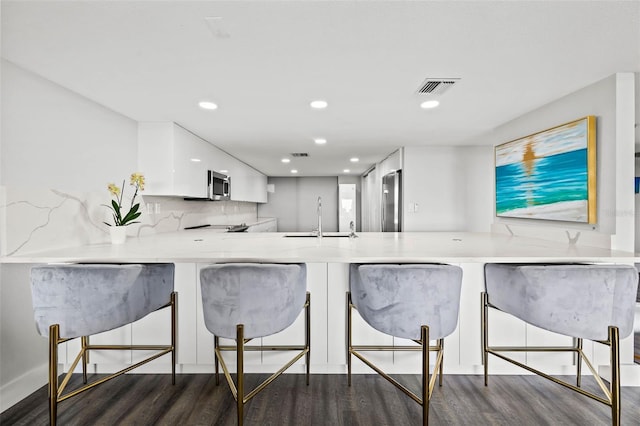 kitchen with kitchen peninsula, white cabinetry, sink, and dark wood-type flooring