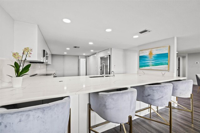 kitchen featuring a kitchen breakfast bar, dark hardwood / wood-style flooring, white cabinetry, and kitchen peninsula