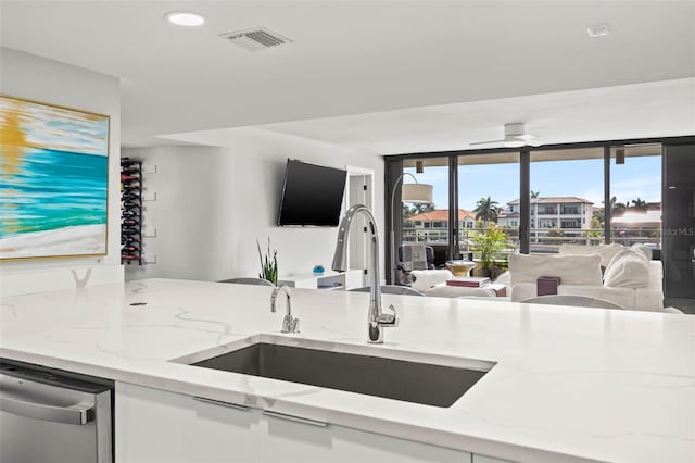 kitchen with light stone countertops, stainless steel dishwasher, and sink