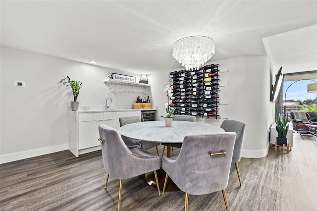 dining room featuring wet bar, wood-type flooring, wine cooler, and an inviting chandelier