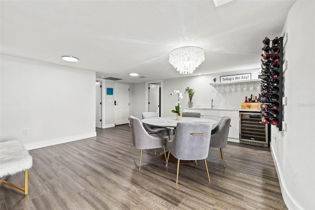 dining area with dark hardwood / wood-style flooring, a textured ceiling, beverage cooler, indoor wet bar, and a chandelier