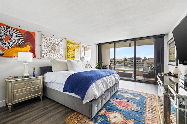 bedroom with access to exterior, a textured ceiling, dark hardwood / wood-style flooring, and floor to ceiling windows